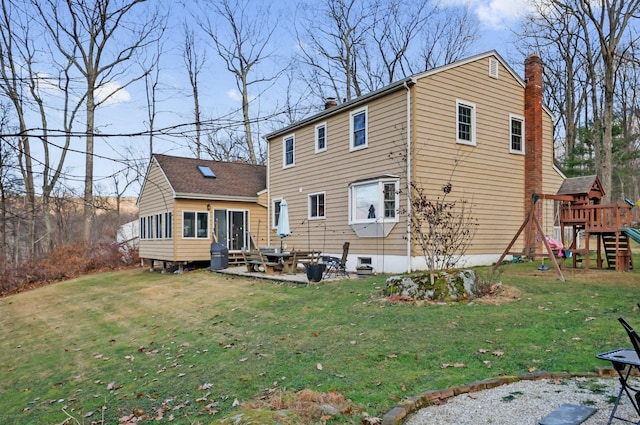 rear view of property featuring a playground, a lawn, and a patio