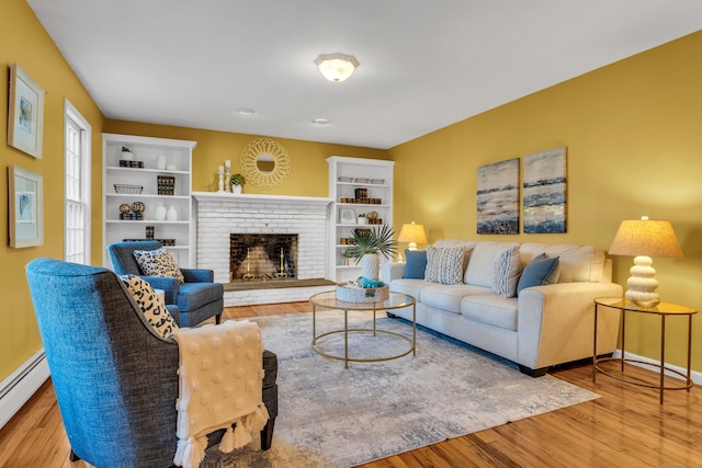 living room with light hardwood / wood-style flooring, a baseboard heating unit, and a brick fireplace