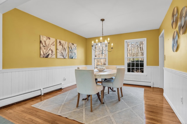 dining area featuring light hardwood / wood-style flooring, a notable chandelier, and a baseboard heating unit