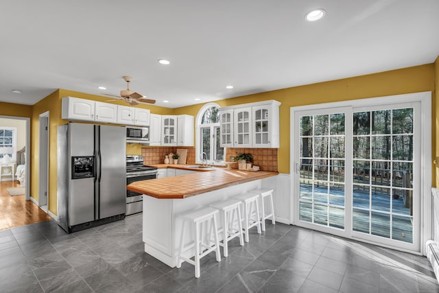 kitchen featuring kitchen peninsula, appliances with stainless steel finishes, sink, white cabinets, and a breakfast bar area