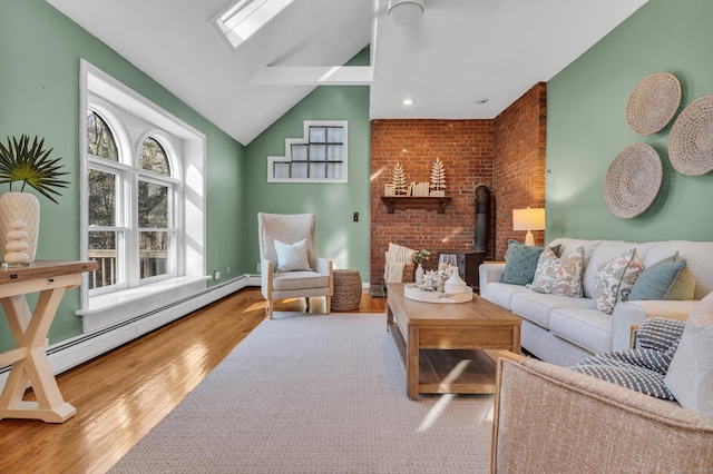 living room with a wood stove, a baseboard radiator, brick wall, hardwood / wood-style floors, and vaulted ceiling with skylight