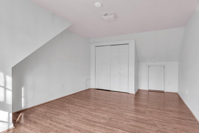 additional living space with hardwood / wood-style flooring and vaulted ceiling