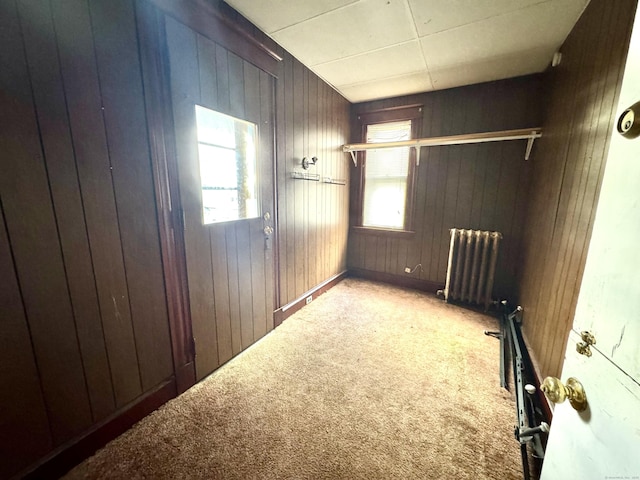 carpeted spare room with radiator and wooden walls