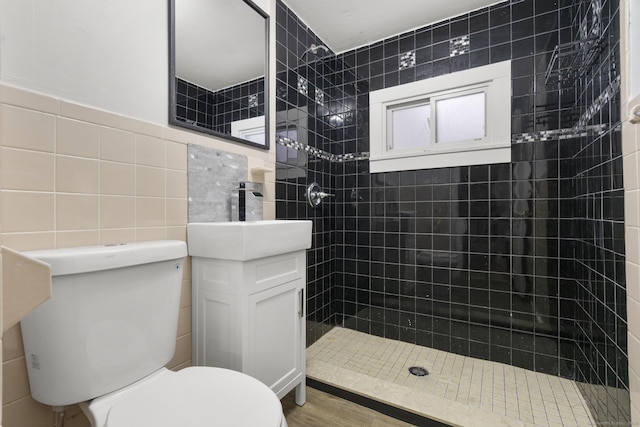 bathroom featuring tiled shower, toilet, tile walls, and vanity