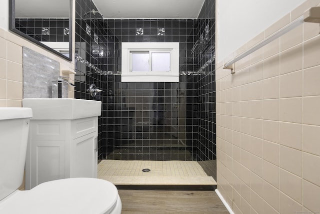 bathroom with a tile shower, vanity, and toilet