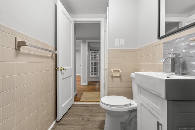 bathroom with hardwood / wood-style flooring, vanity, toilet, and tile walls