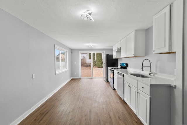 kitchen with hardwood / wood-style floors, white cabinetry, sink, and appliances with stainless steel finishes