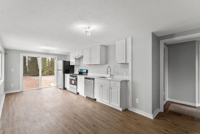 kitchen with white cabinets, sink, stainless steel appliances, and hardwood / wood-style floors