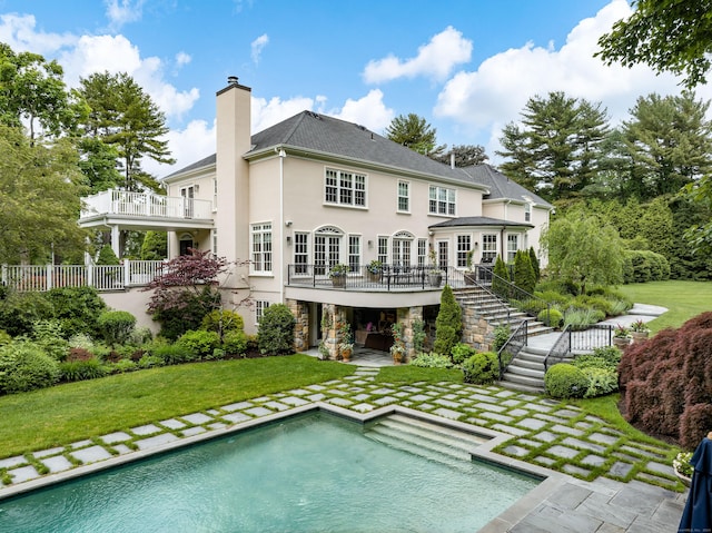 rear view of house with a yard, a balcony, and a patio