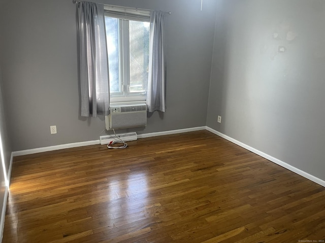 unfurnished room featuring a baseboard heating unit, cooling unit, and dark wood-type flooring