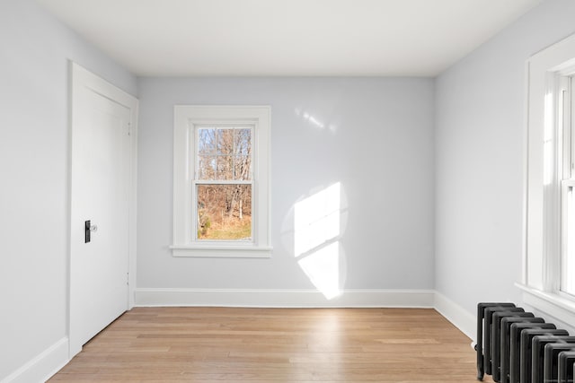 empty room featuring radiator and light hardwood / wood-style flooring