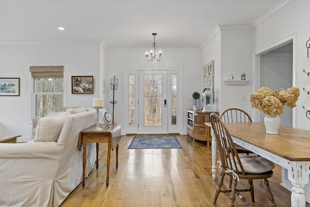 entrance foyer with a notable chandelier, crown molding, and light hardwood / wood-style flooring