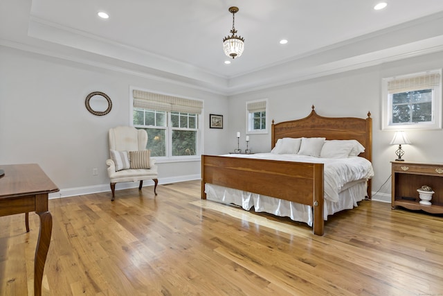 bedroom with a raised ceiling, a chandelier, light wood-type flooring, and ornamental molding