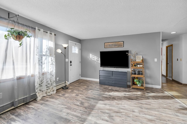 entrance foyer with hardwood / wood-style flooring, baseboard heating, and a textured ceiling