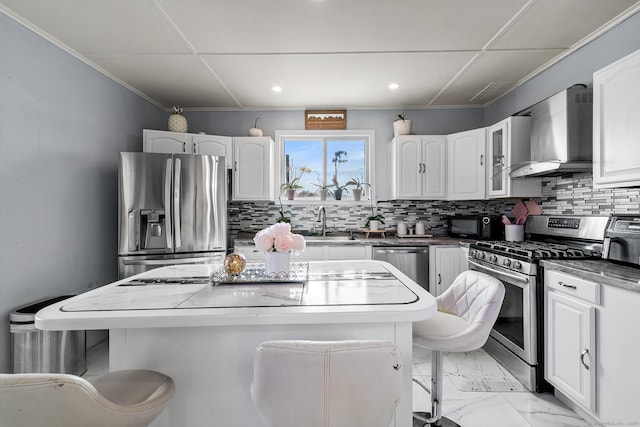 kitchen featuring decorative backsplash, appliances with stainless steel finishes, a kitchen breakfast bar, and wall chimney range hood