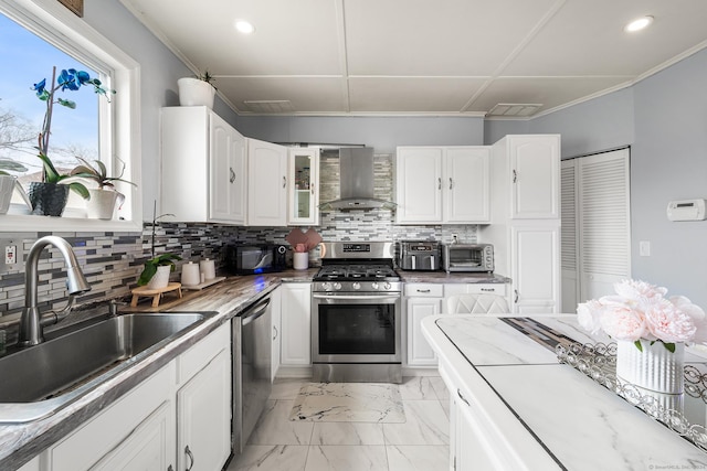 kitchen with backsplash, wall chimney range hood, sink, white cabinetry, and stainless steel appliances