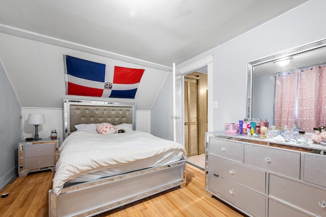 bedroom featuring a closet, light hardwood / wood-style flooring, and lofted ceiling