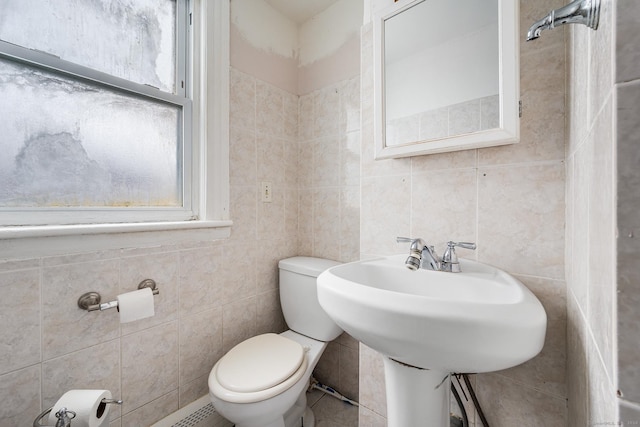 bathroom featuring sink, toilet, and tile walls