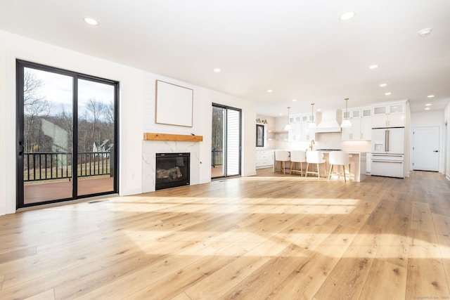 unfurnished living room featuring a premium fireplace, sink, and light hardwood / wood-style floors