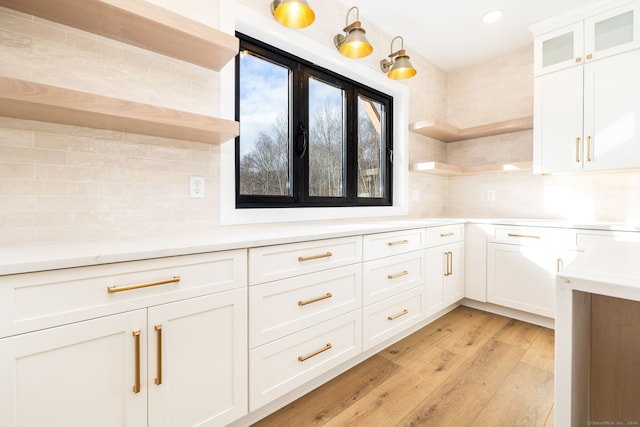 kitchen with white cabinets, light wood-type flooring, and tasteful backsplash