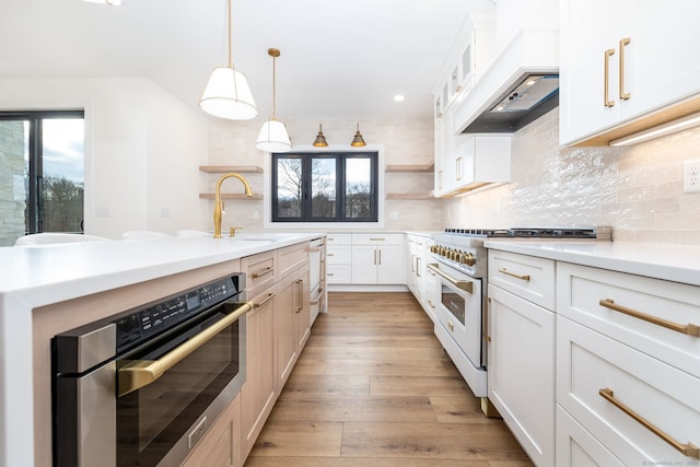 kitchen featuring white cabinets, range with gas cooktop, oven, and hanging light fixtures