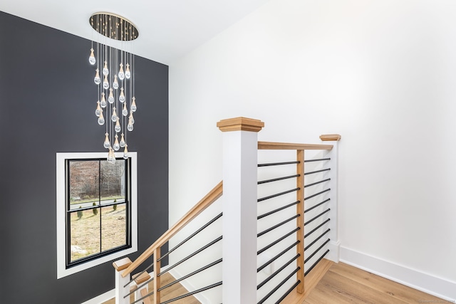 stairs with hardwood / wood-style floors and a notable chandelier