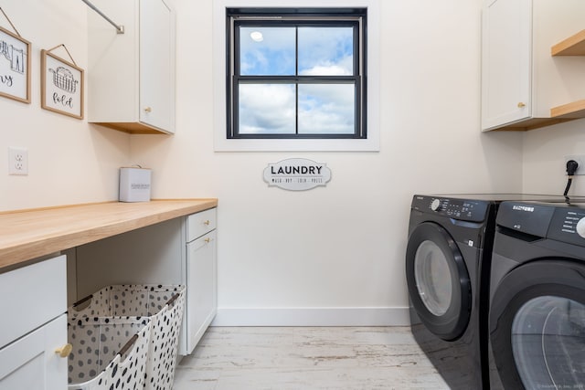 clothes washing area with cabinets, washing machine and dryer, and light wood-type flooring