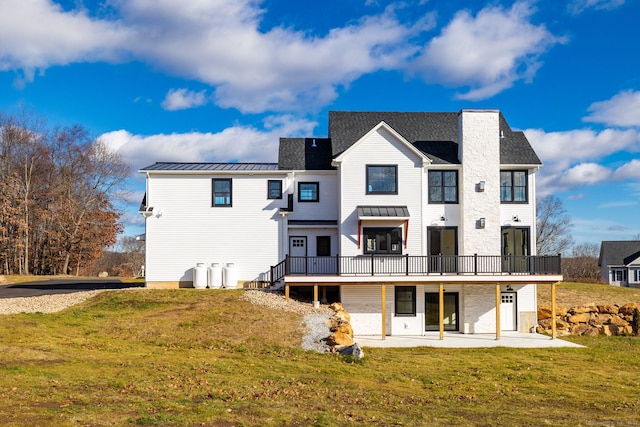 rear view of property featuring a patio, a wooden deck, and a lawn