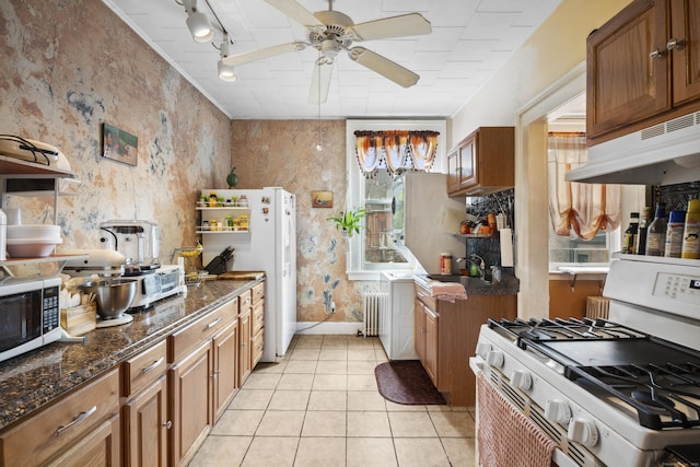 kitchen featuring radiator, ceiling fan, rail lighting, white appliances, and light tile patterned floors