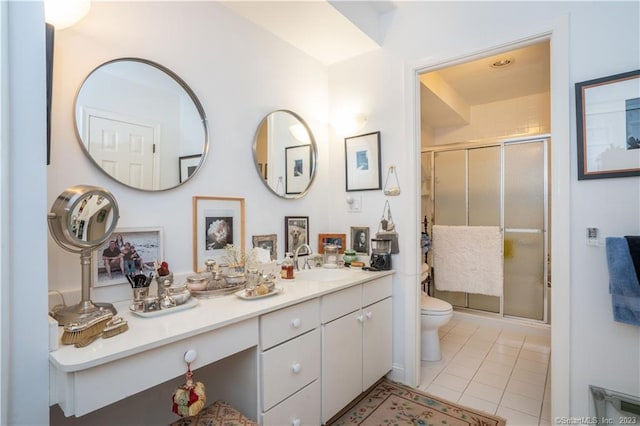 bathroom with tile patterned flooring, vanity, toilet, and a shower with door