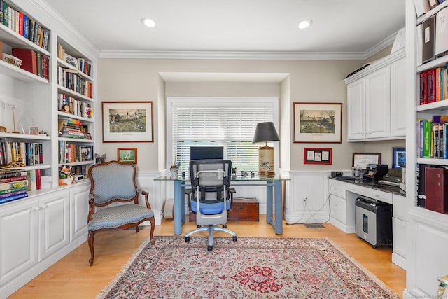 home office with light hardwood / wood-style flooring, built in desk, and ornamental molding