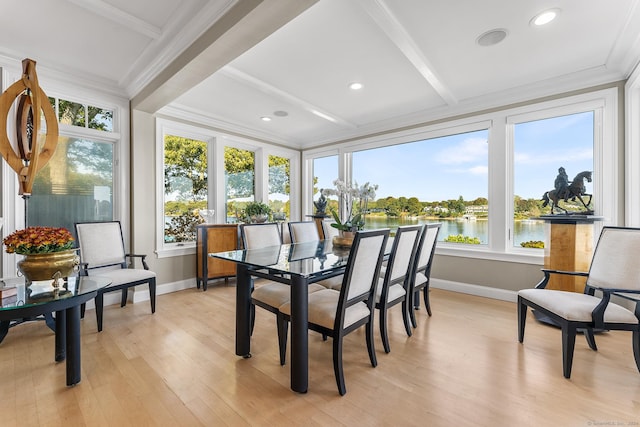 sunroom with plenty of natural light, beam ceiling, and a water view