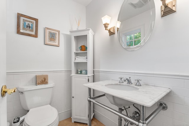 bathroom featuring tile patterned flooring, toilet, tile walls, and sink