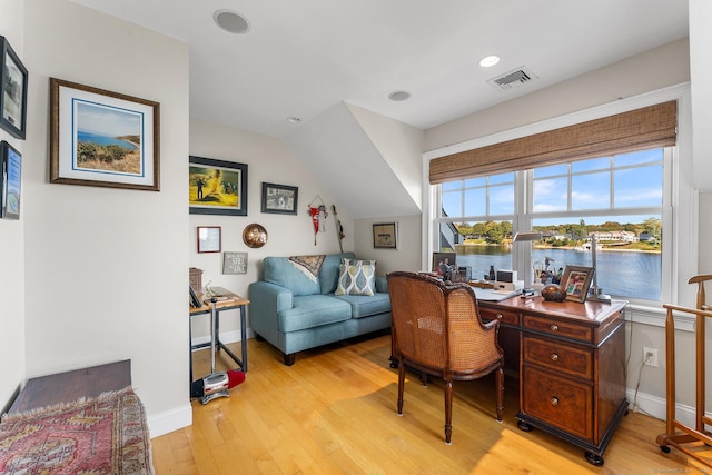 office featuring a water view, lofted ceiling, and light wood-type flooring