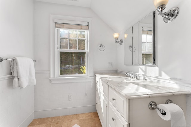 bathroom with vaulted ceiling, plenty of natural light, and tile walls