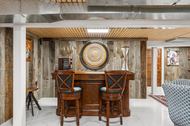 wine area featuring bar area and wood walls