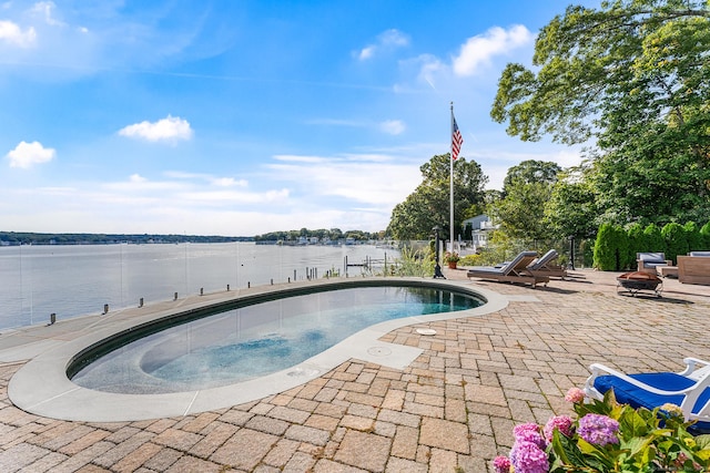 view of pool with a patio area, a water view, and a fire pit