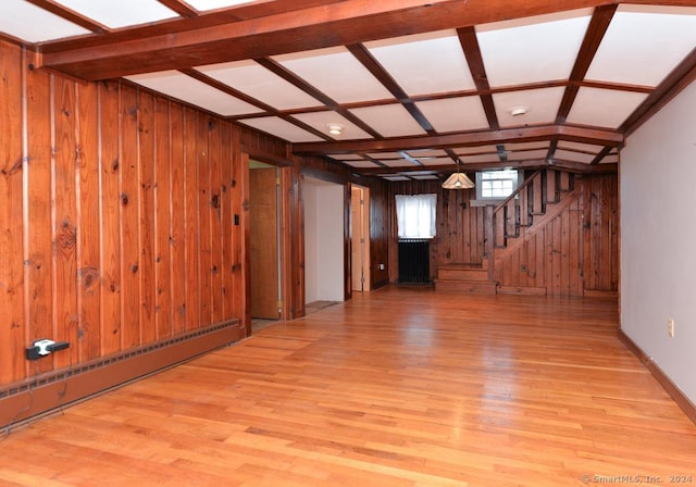 basement with light wood-type flooring, wooden walls, and a baseboard radiator