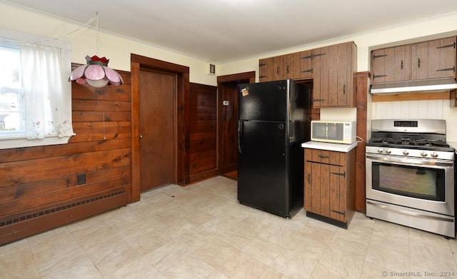 kitchen featuring black refrigerator, crown molding, and gas range