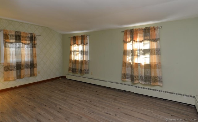 empty room with dark wood-type flooring and a baseboard heating unit