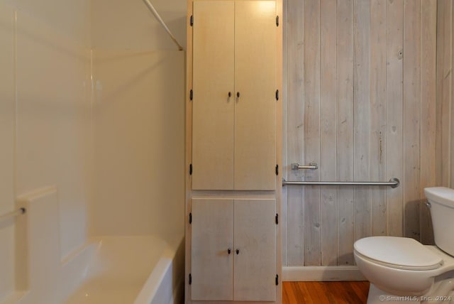 bathroom with hardwood / wood-style floors, separate shower and tub, toilet, and wooden walls