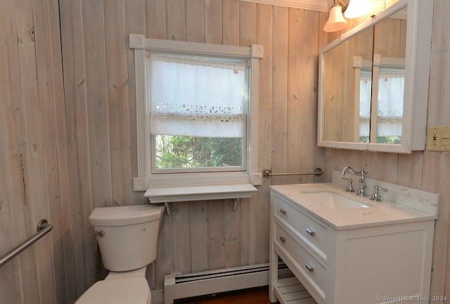 bathroom featuring wood walls, toilet, vanity, and a baseboard heating unit