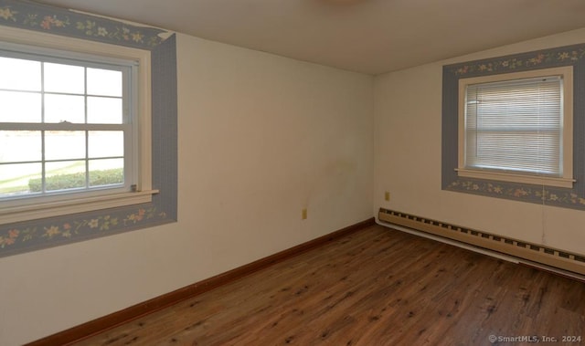 unfurnished room featuring baseboard heating and dark wood-type flooring