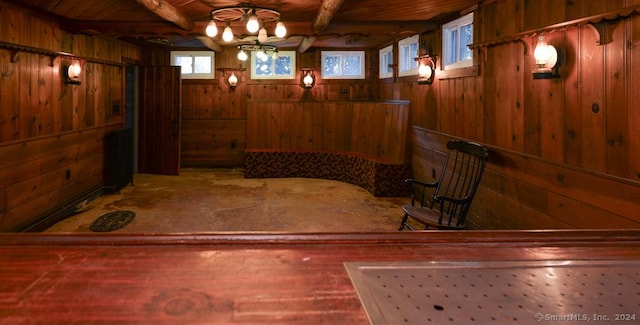 interior space featuring beamed ceiling, wood walls, and wooden ceiling