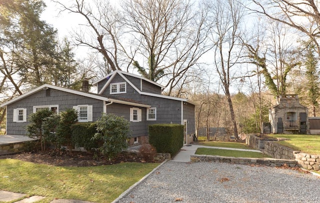 view of front facade featuring a front yard and an outdoor stone fireplace