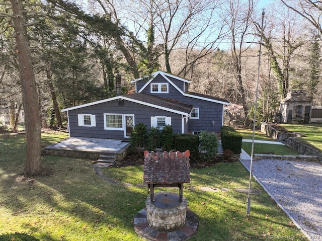 bungalow-style house with a front yard, an outdoor stone fireplace, and a patio area