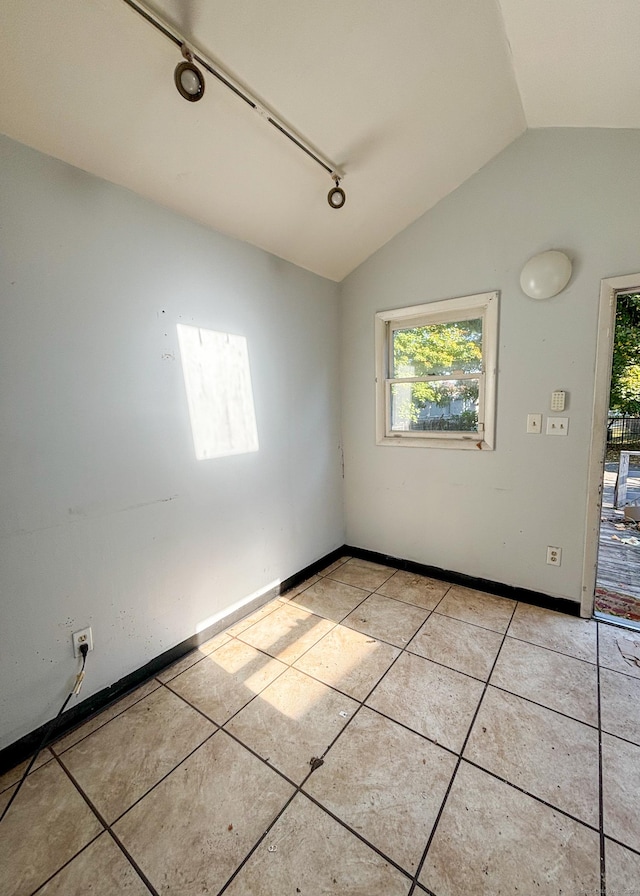 tiled spare room featuring lofted ceiling and rail lighting