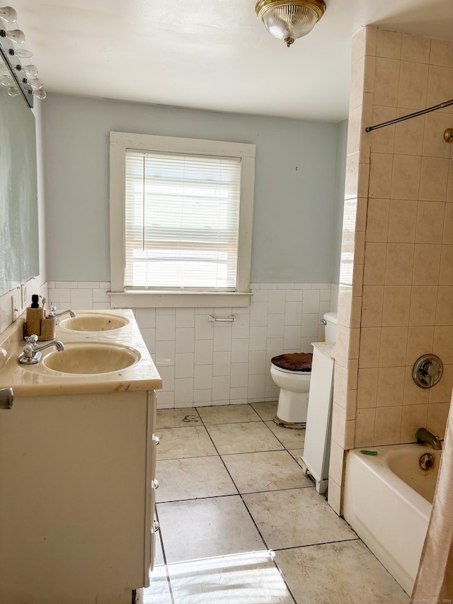 full bathroom with tiled shower / bath combo, tile patterned floors, toilet, vanity, and tile walls