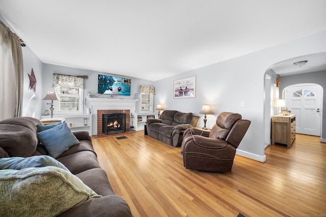 living room with hardwood / wood-style flooring and a brick fireplace