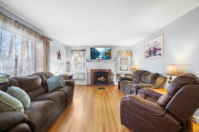 living room with light hardwood / wood-style flooring and a brick fireplace